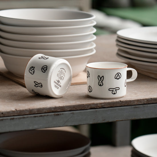 White ceramic mugs with black patterns on a wooden table