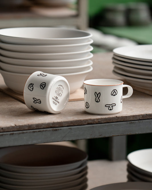 White ceramic mugs with black patterns on a wooden table