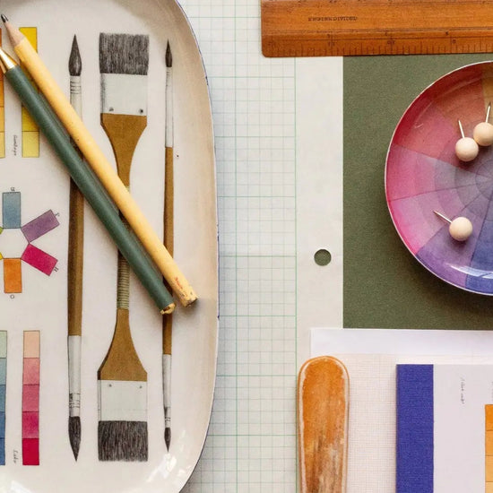 Art supplies including brushes, a color wheel, and a ruler on a green surface.