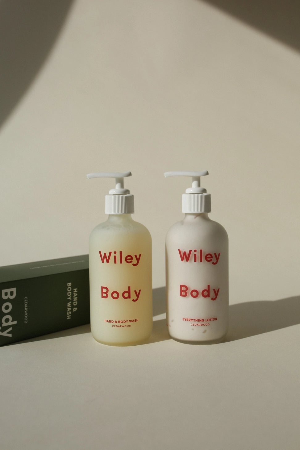 Two bottles of Wiley Body products on a neutral background