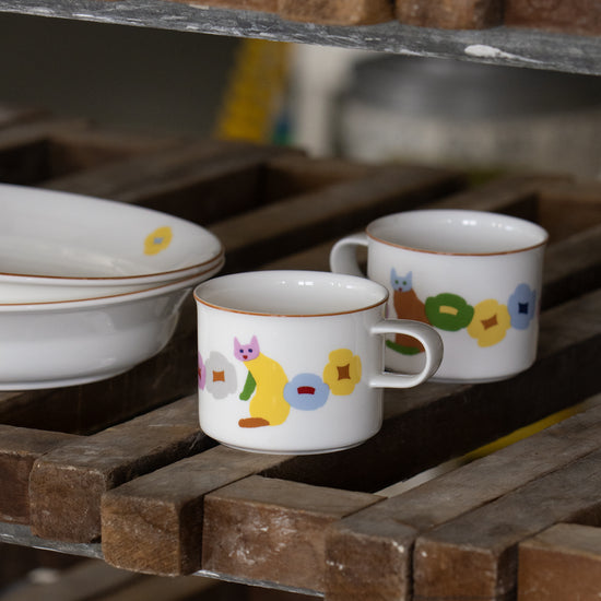 Two ceramic cups with colorful designs on a wooden surface