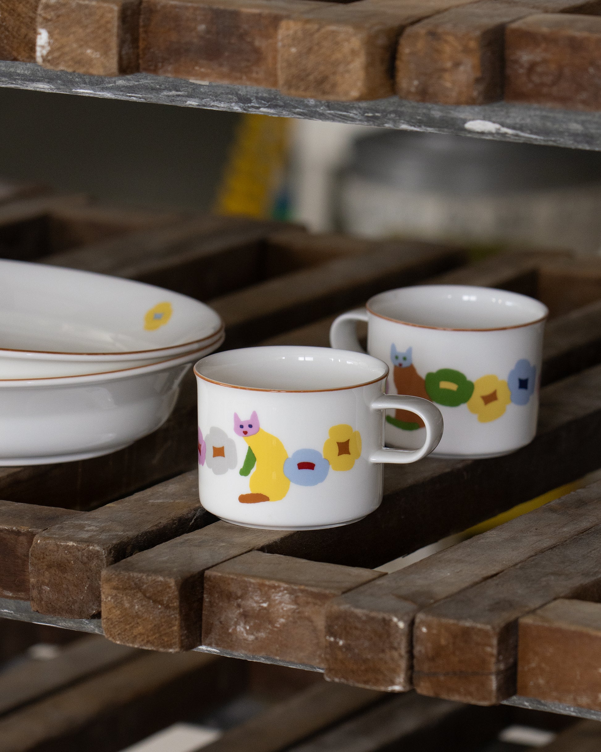 Two ceramic cups with colorful designs on a wooden surface