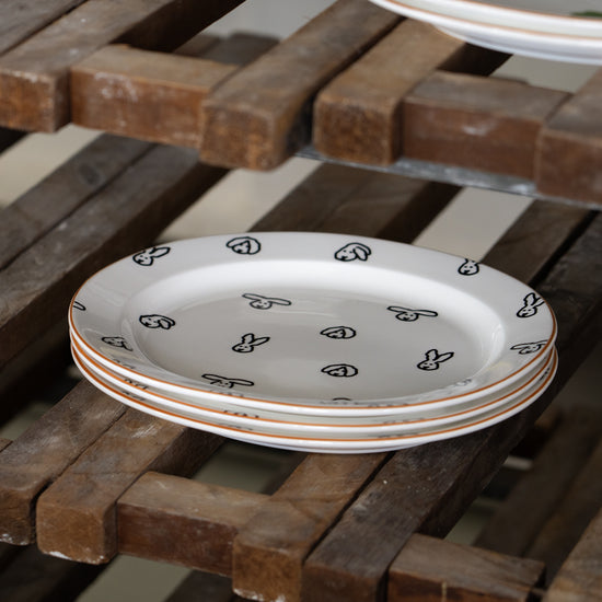 Stack of decorative plates with black patterns on a wooden surface