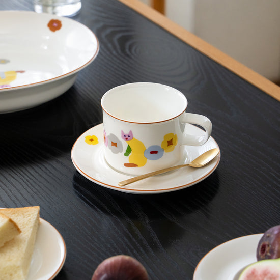 Cup with saucer on a table with bread and fruit