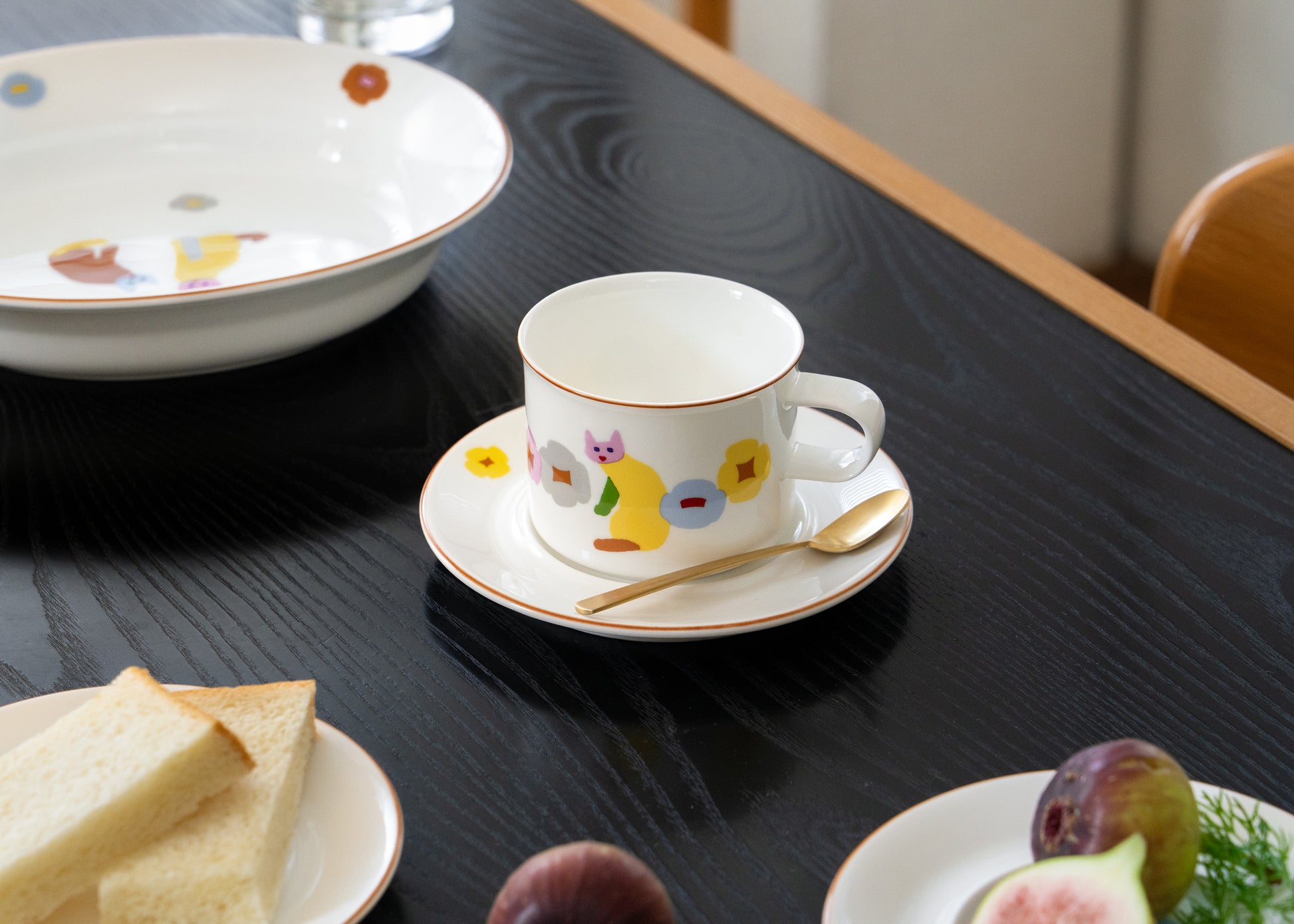 Cup with saucer on a table with bread and fruit