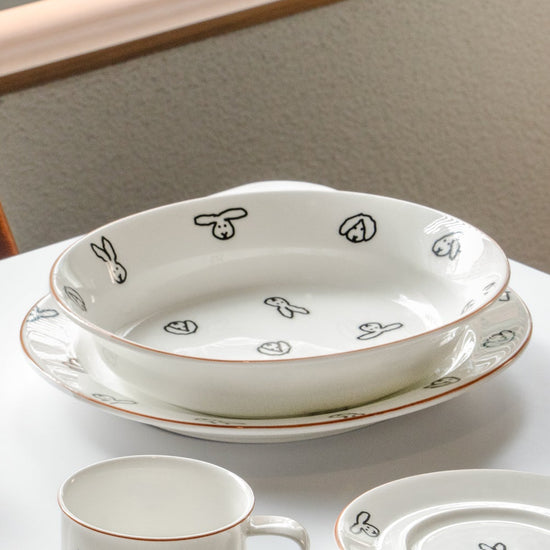 White ceramic dishes with black floral patterns on a light surface.