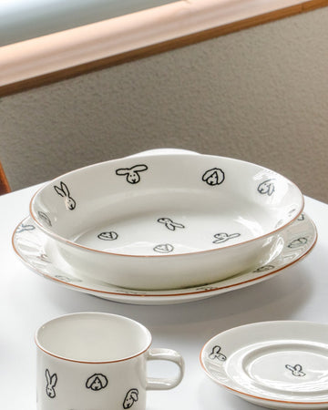 White ceramic dishes with black floral patterns on a light surface.