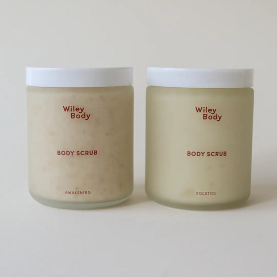 Two frosted glass jars of Wiley Body Body Scrub with white lids, shown side by side on a light beige background.