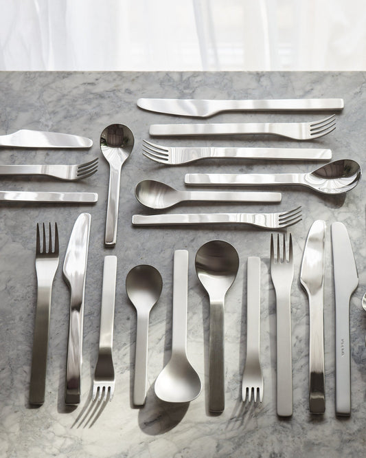 Stainless steel cutlery set on a gray marble surface