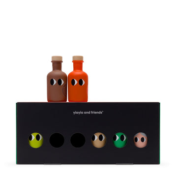 Two small bottles of olive oil on a black package with set items