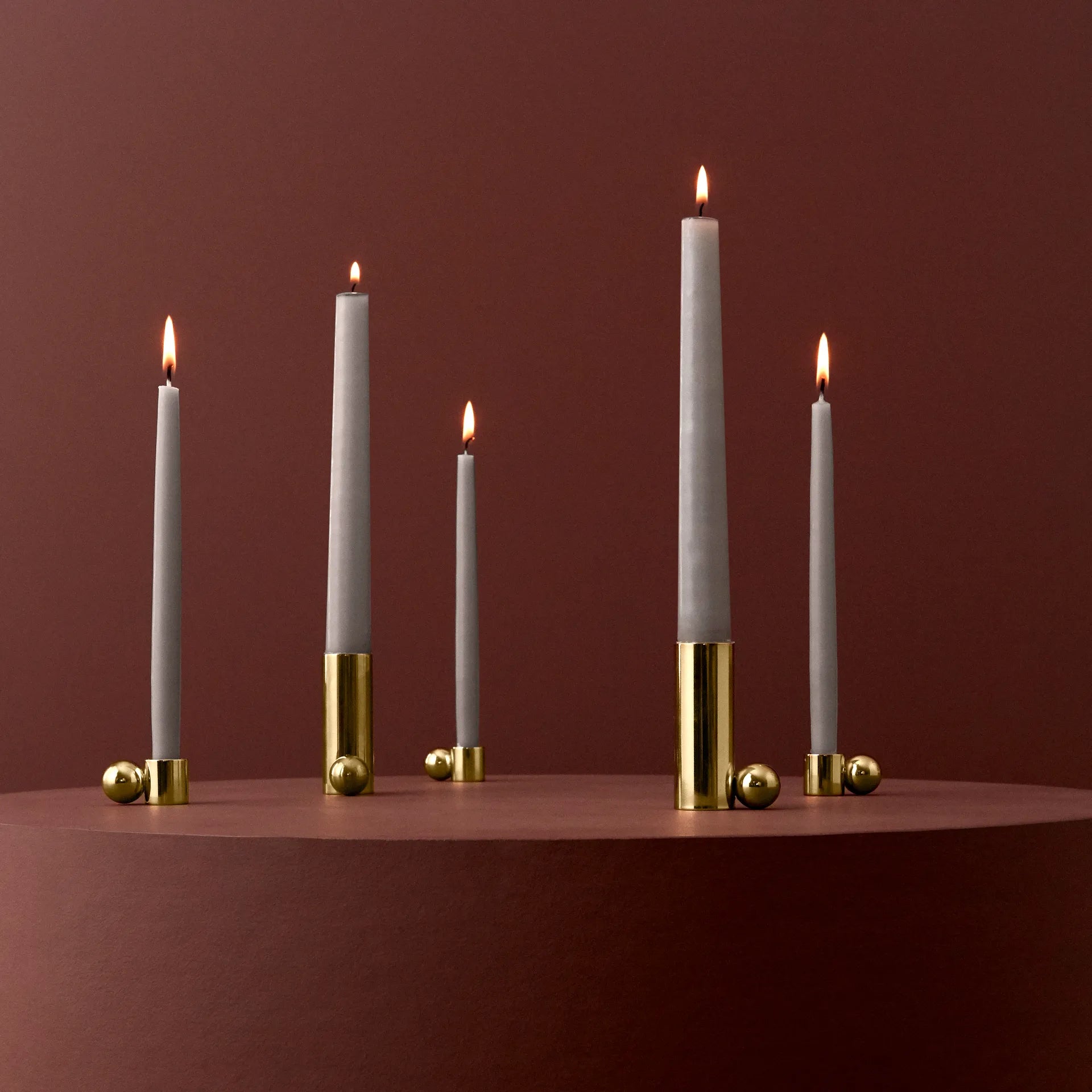 Set of candles with gold candle holder on a red background