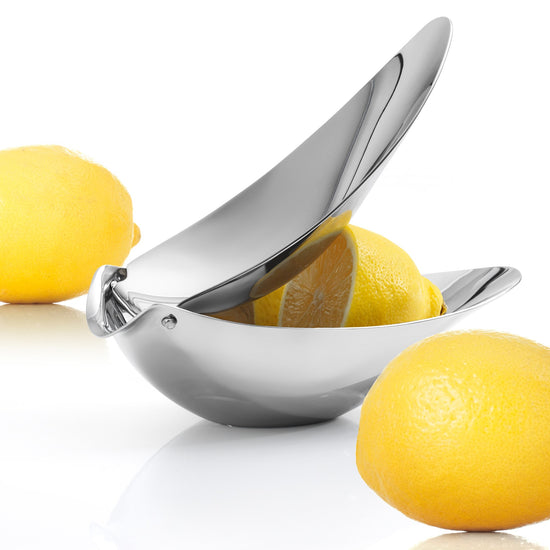 Metallic lemon squeezer with lemons on a white background