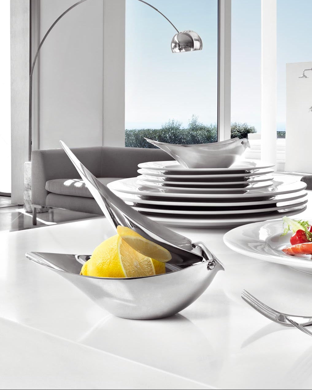 Modern kitchen with white countertops, plates, and a view of the outdoors.