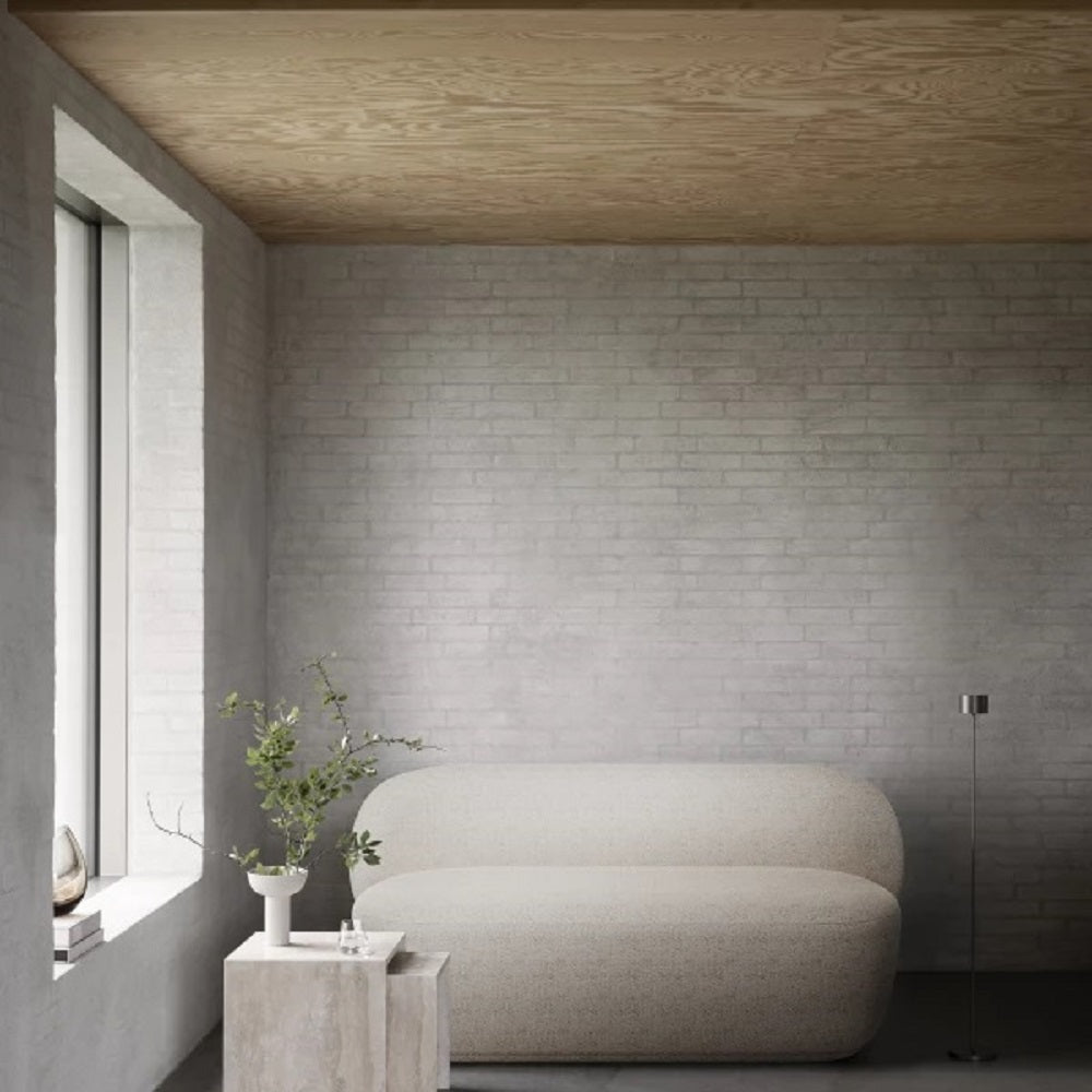 Modern interior with a curved beige sofa against a gray brick wall.