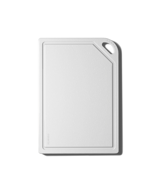 A minimalist white cutting board with a raised border and a small cutout handle in the top-right corner, shown on a clean white background with a soft drop shadow.