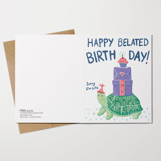 Greeting card with turtle and gift box illustration and 'Happy Belated Birthday!' text on a white background.