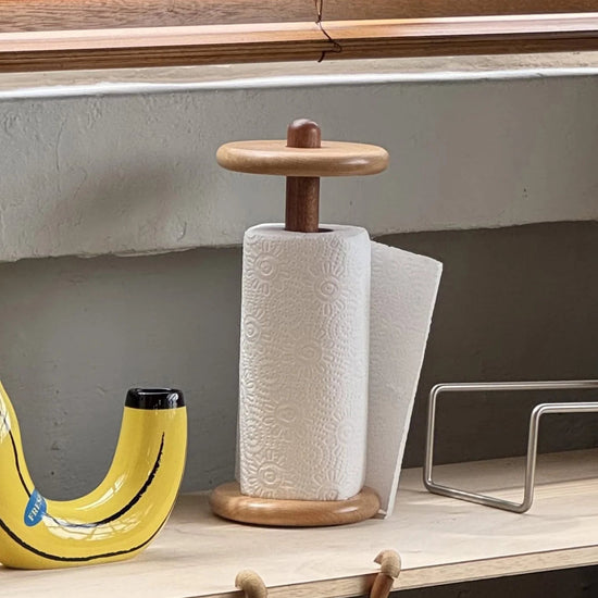 Wooden banana-shaped bottle opener and paper towel holder on a shelf with a monkey figurine.