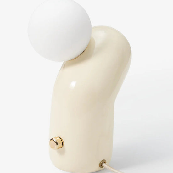 Modern table lamp with a white spherical shade and beige base on a light gray background