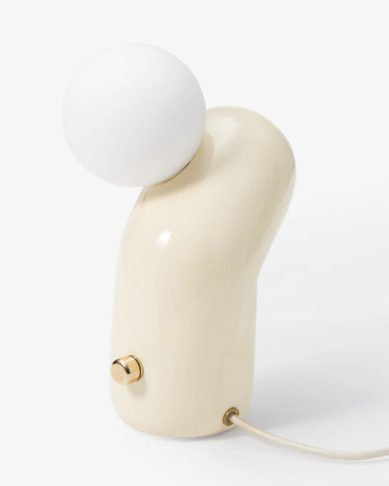 Modern table lamp with a white spherical shade and beige base on a light gray background