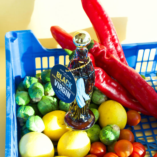 Basket of fresh produce with a bottle labeled 'Black Virgin' on a white background