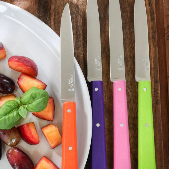 Set of four colorful knives with fruit on a plate