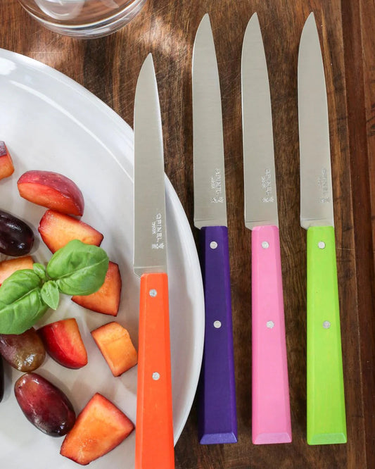 Set of four colorful knives with fruit on a plate