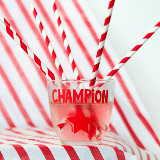 Glass with red liquid and 'Champion' text on a red and white striped background