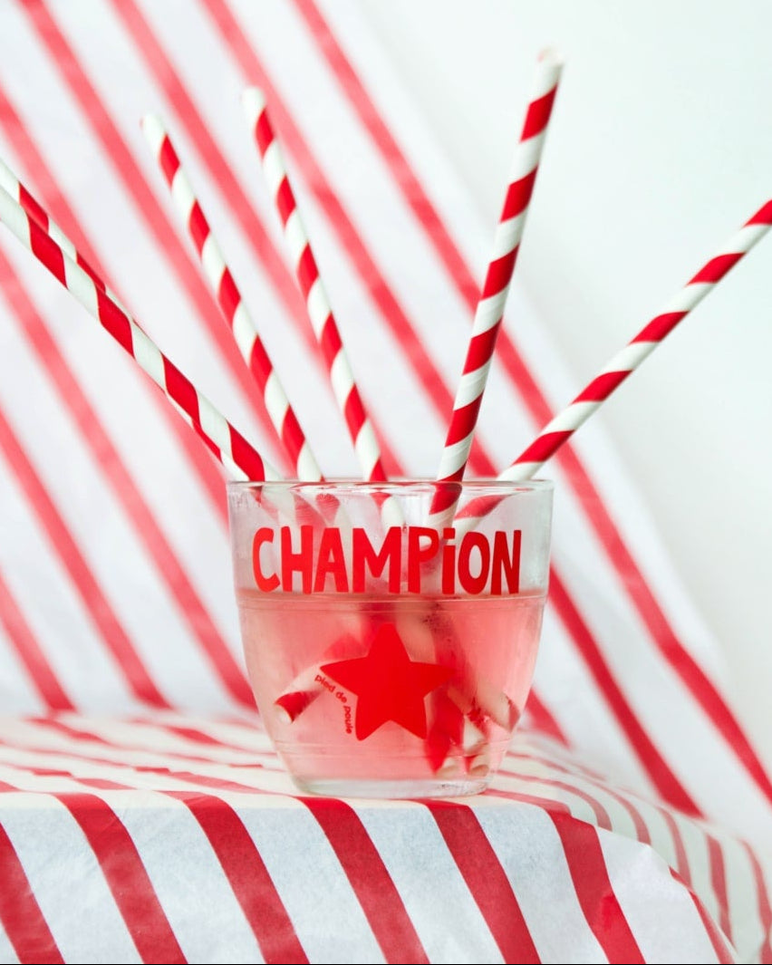 Glass with red liquid and 'Champion' text on a red and white striped background