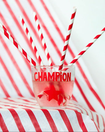 Glass with red liquid and 'Champion' text on a red and white striped background