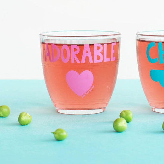 Two glasses with 'ADORABLE' and 'CHOU' text on a light blue background with green peas.