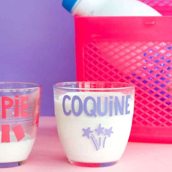 Two cups labeled 'CHIPIE' and 'COQUINE' with a pink container on a purple background.