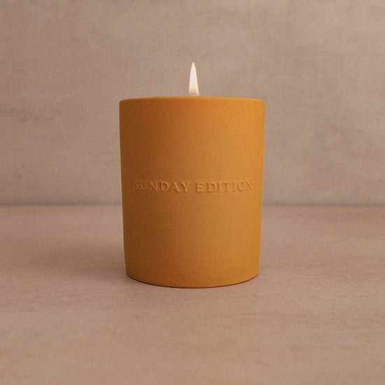 Yellow candle with 'Sunday Edition' branding on a beige background