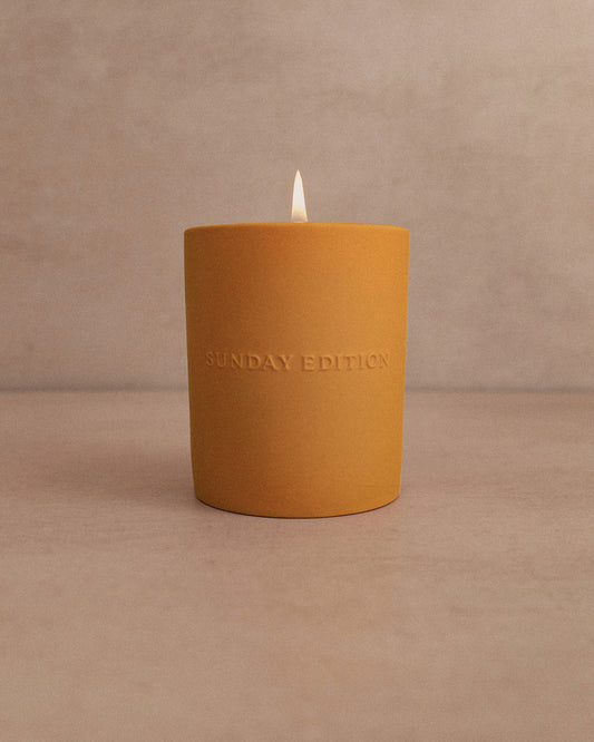 Yellow candle with 'Sunday Edition' branding on a beige background