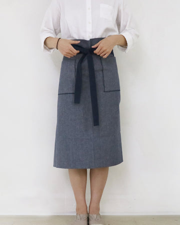 a woman wearing a denim bistro apron and white shirt