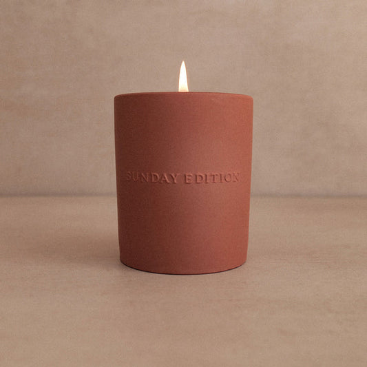 Red candle with 'Sunday Edition' branding on a beige background