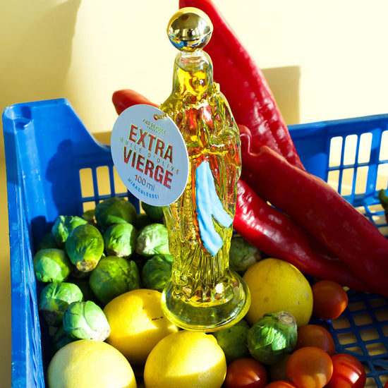 Bottle of olive oil with a 'Extra Viejo' label surrounded by fruits and vegetables in a blue basket.