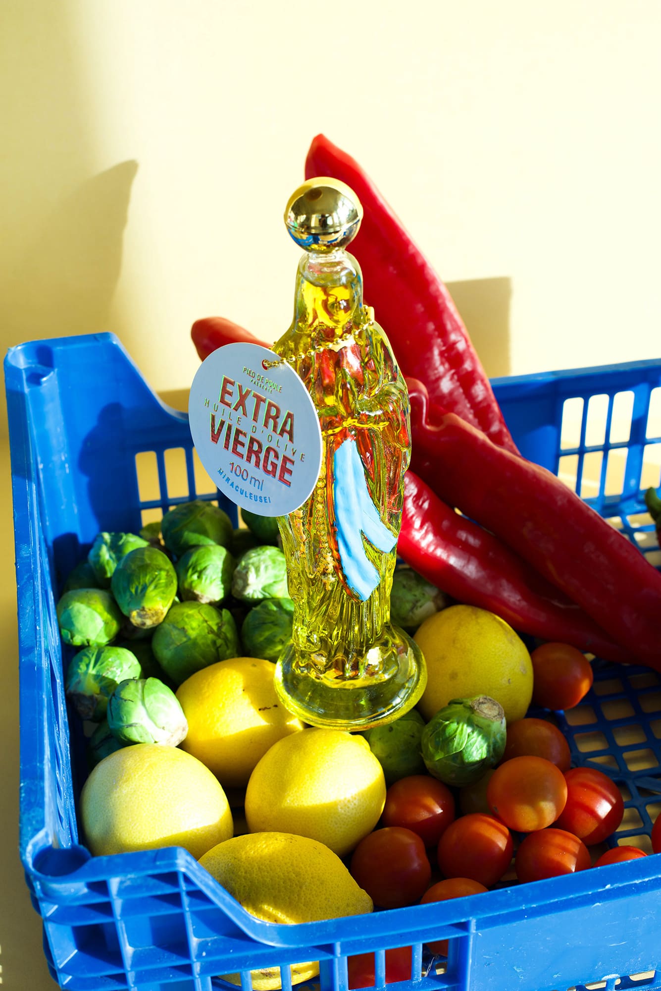 Bottle of olive oil with a 'Extra Viejo' label surrounded by fruits and vegetables in a blue basket.