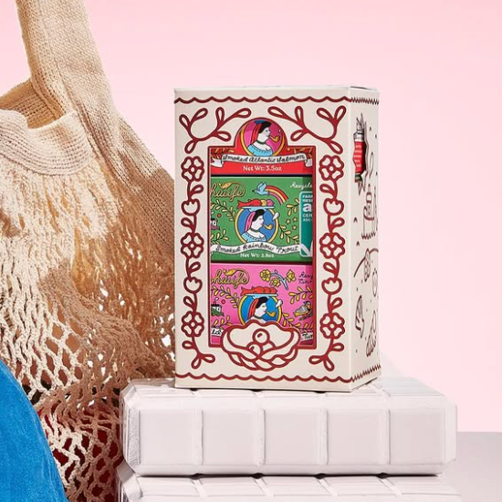 Blue cap, beige mesh bag, and boxes with colorful designs on a pink background