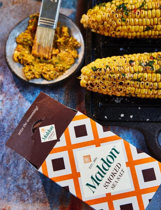 Maldon smoked sea salt packaging with corn on the cob and seasoning in the background.