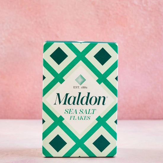 Maldon sea salt flakes packaging with geometric design on a pink background