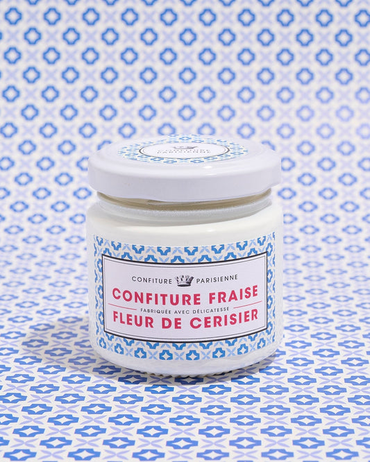 A jar of strawberry and cherry blossom jam with a blue patterned label against a matching patterned background