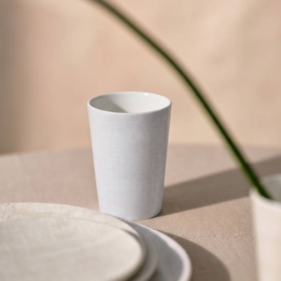 White ceramic cup and saucer on a beige surface with a soft focus background