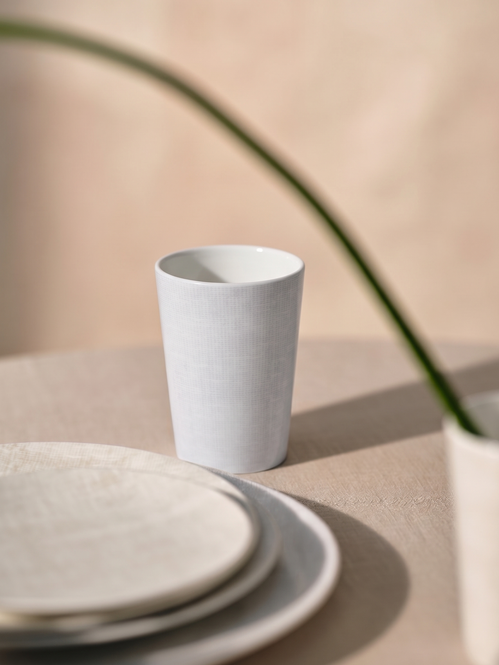 White ceramic cup and saucer on a beige surface with a soft focus background