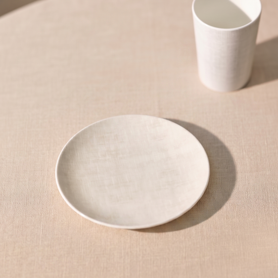 Minimalist white ceramic plate and cup on a beige surface