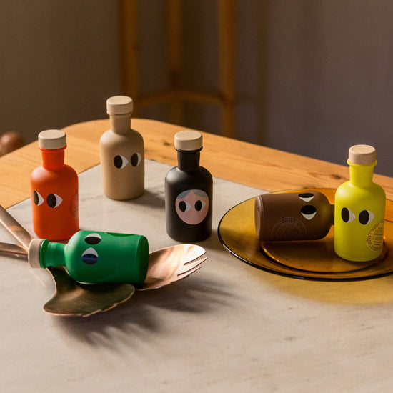 Colorful olive oils on a wooden table with a neutral background