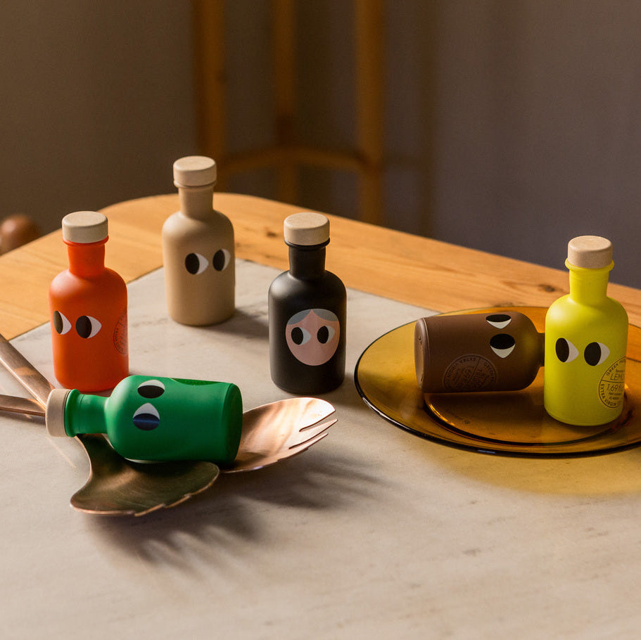 Colorful olive oils on a wooden table with a neutral background