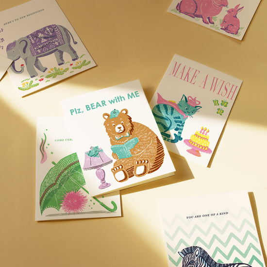 Collection of colorful greeting cards with animal illustrations on a beige surface