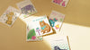 Collection of colorful greeting cards with animal illustrations on a beige surface