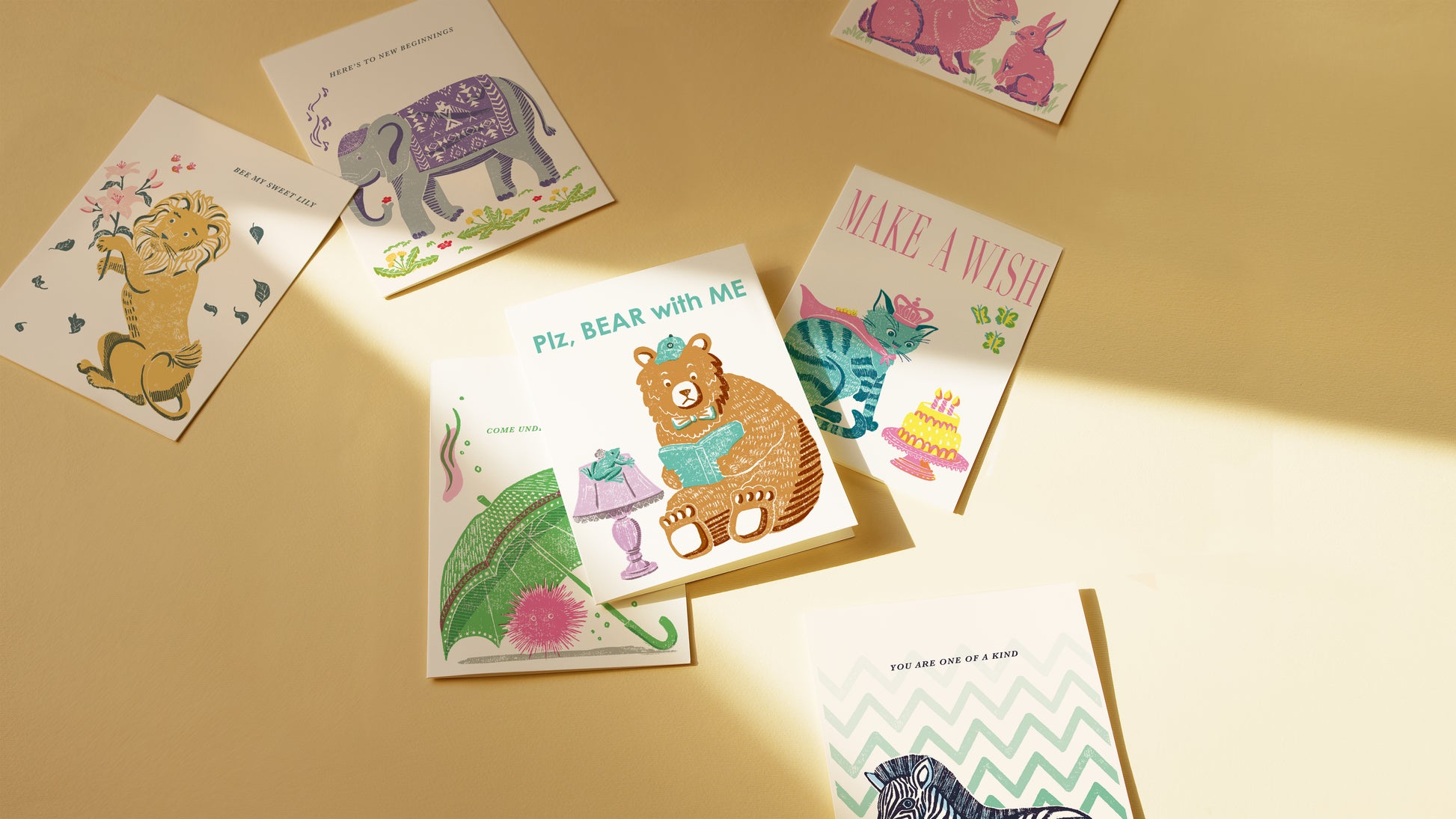 Collection of colorful greeting cards with animal illustrations on a beige surface