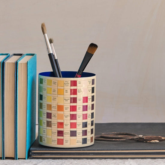 Desk setup with stationery items including books, cups, and a vase.